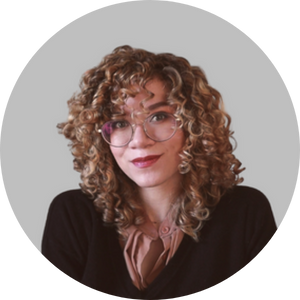woman with curly hair and glasses smiles at the camera