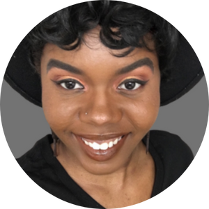 a Black woman in a black hat smiles at the camera
